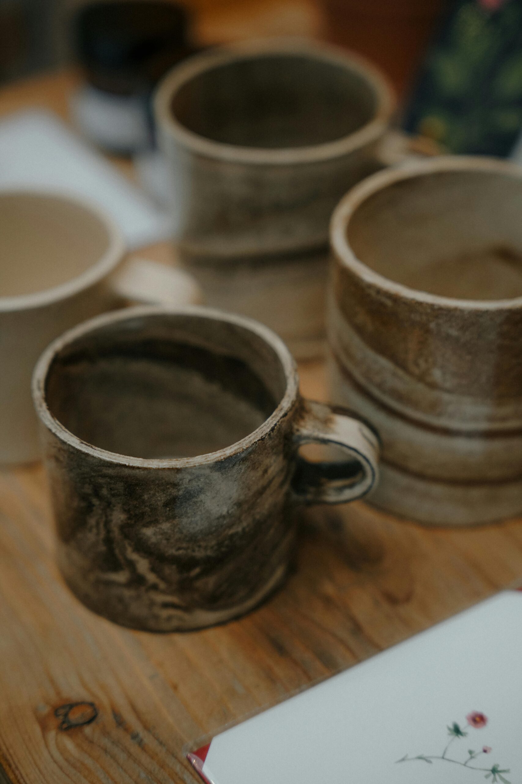 Handcrafted ceramic mugs displayed on a rustic wooden table, showcasing artisanal craftsmanship, in Amsterdam.