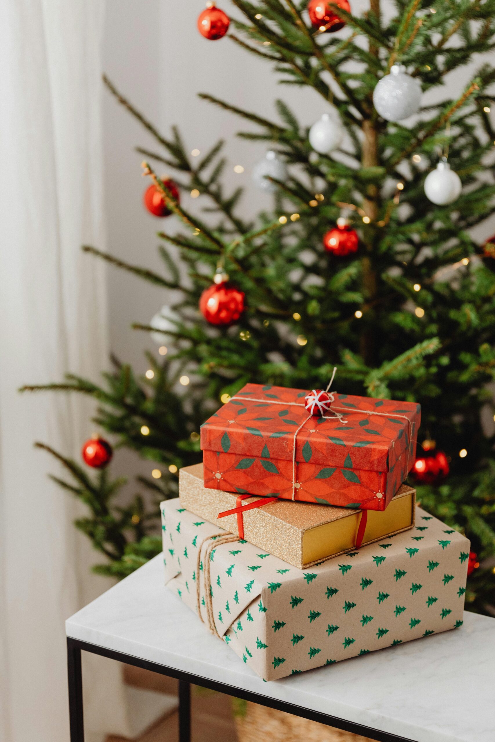 Christmas tree adorned with ornaments and stacked gift boxes, perfect for the holiday season.